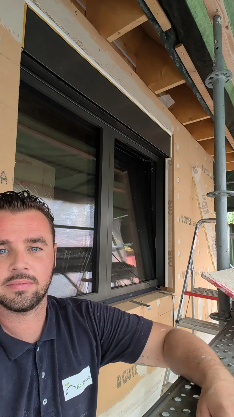 Houtvezelplaten op een gevel met de aansluiting bij het kozijn, Tim op de steiger