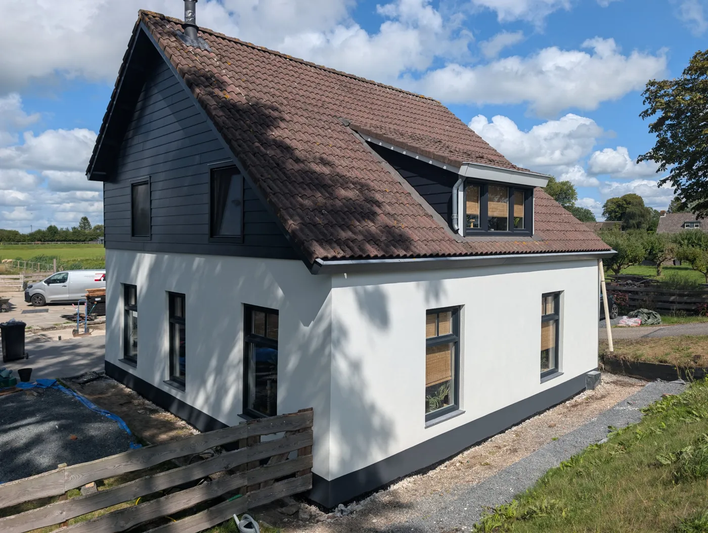 Dezelfde woning met een witte kalkgevel en een donkere plint