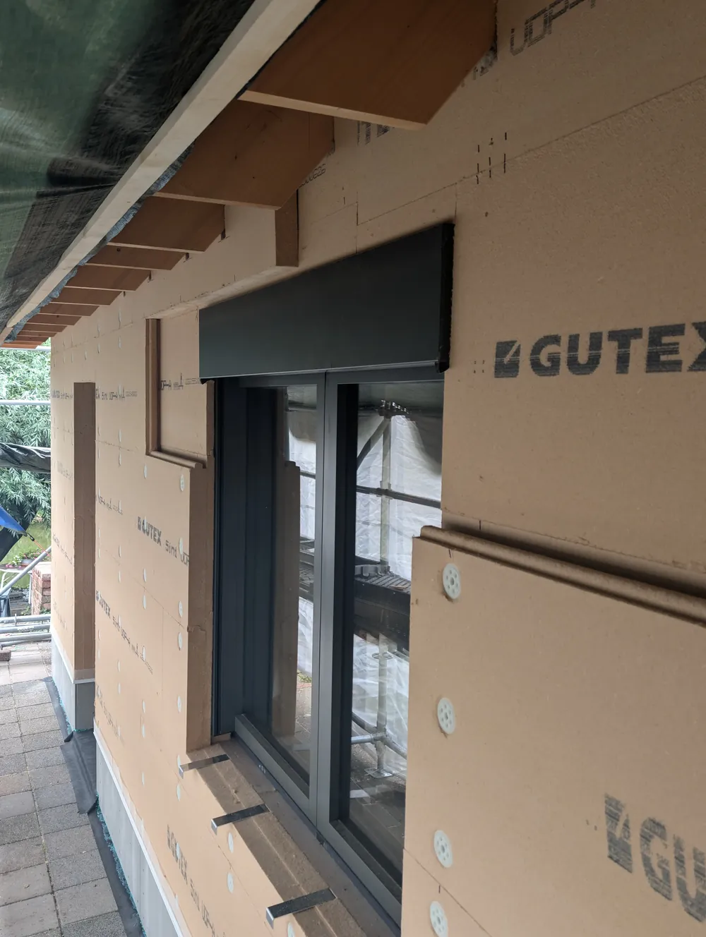 Houtskeletbouwgevel met Gutex Thermowall 5in1: platen in verband, gesponningde dagkantstroken rond het kozijn en vensterbankdragers klaar voor de waterkering.